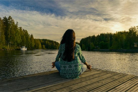 Passive meditation music - woman sitting relaxed on jetty meditating